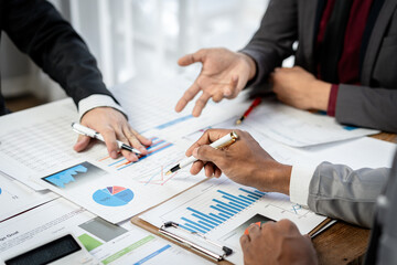 Fototapete - Three people are sitting at a table with a lot of papers and graphs