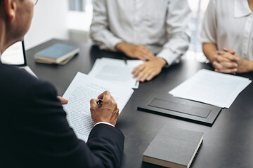 Aufkleber - A man is writing on a piece of paper in front of a table with three other people