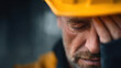 © Nakarin - Close up of male construction worker with yellow safety helmet showing tired or stressed expression eyes closed and hand resting face conveying fatigue or concern emotional moment professional
