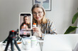 © shurkin_son - Indoor image with selective focus on aged woman nutritionist holding bottle of food supplement and recording video for social media, sharing her knowledge and giving advice on how to stay healthy