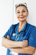 © shurkin_son - Vertical closeup portrait of smiling confident Caucasian aged general practitioner or pediatrician in blue uniform with stethoscope around her neck posing at camera with smile being pride with her job