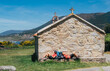 © Soloviova Liudmyla - Couple of pilgrims with backpacks lying and resting on bench next to old church on Camino Portuguese Way, inspiring walk on famous Camino de Santiago. Travel, pilgrimage, lifestyle, architecture