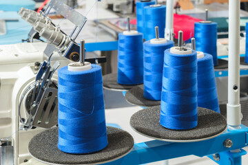 Aufkleber - A group of blue and white spools of thread are being made on a machine. The spools are arranged in a row and are of varying sizes