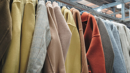 Poster - rack of clothes with a variety of colors and styles. The clothes are hanging on a rack, and the colors include yellow, orange, and brown