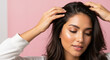 © Vasiliy - Woman with long brown hair massaging scalp with both hands on pink background. Hair care scalp massage beauty routine wellness treatment anti aging dermatology