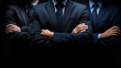 © Curioso.Photography - Three men in dark suits standing side by side, partially lit in a dramatic setting.