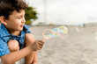 © Djavan Rodriguez - Child having fun making soap bubbles on a sandy beach