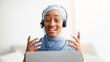 © Prostock-studio - Remote work, communication, education. Happy Muslim lady in hijab wearing headset, having video call on laptop at home. Young Arab woman talking on web at home, taking part in business web conference