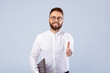 © Prostock-studio - Bearded young businessman with laptop computer offering hand for handshake on grey studio background. Millennial manager with pc proposing business deal or agreement