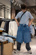 © Светлана Мищенко - Teenager holding shorts while shopping in clothing store. Young customer shopping trendy casual wear at fashion retail shop. Teenage consumer making fashion choices. Boy shopping alone. Copyspace