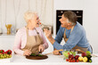 © Prostock-studio - Cheerful Elderly Husband Feeding Wife Having Fun Cooking And Tasting Dinner Standing In Kitchen At Home. Senior Spouses Enjoying Dinner Preparation Together Indoors. Older Family Recipes Concept