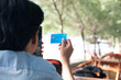 © AnnaJannah - Back View Happy Asian Young businessman hold blue creditcard and phone purchasing online shopping in outdoor cafe.