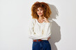 © SHOTPRIME STUDIO - Woman with curly hair in a casual white sweater against a light background, showcasing a relaxed and confident pose, perfect for lifestyle and fashion themes