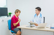 © R Photography - An experienced Asian male doctor consults with a male patient in a red shirt about men's health concerns. He explains a medical form, providing expert advice on urology and related health conditions
