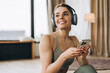 © Maria Vitkovska - Young sportswoman wearing headphones and holding smartphone is choosing music for training