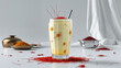 © Ali Khan - A saffron milkshake in a glass with a straw and saffron threads scattered on a white surface around it