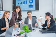 © panomporn - Group of business partners gathered around open laptop discussing company development strategies in modern office.