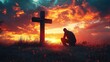 © btiger - Person kneeling in prayer or reflection beside a wooden cross on a grassy hill during a dramatic fiery sunset with vibrant orange and red clouds