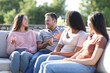 © Antonioguillem - Four friends talking sititng in exterior couch in a terrace