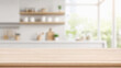 © zetrum - Empty light wood tabletop in front of a bright, softly blurred kitchen interior with shelves, utensils, and natural window light..