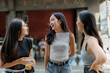 © Phimwilai - Three young women talking and laughing together outdoors