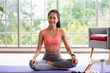 © weedezign - young healthy asian woman practice yoga on a mat at home in a yoga sitting position