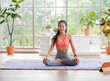 © weedezign - young healthy asian woman practice yoga on a mat at home in a yoga sitting position