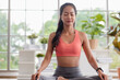 © weedezign - young healthy asian woman practice yoga on a mat at home in a yoga sitting position