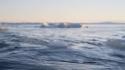 Wall Mural - drifting ice floes casting soft reflections across freezing lake surface during golden sunset, showc