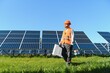 © Serhii - Worker walking in solar panel farm carrying equipment