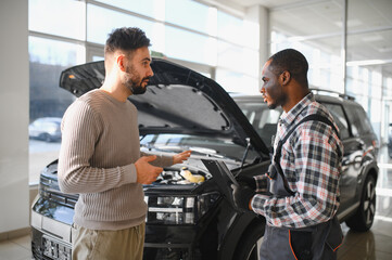 Fototapete - Man on the result of the work of a mechanic. The client evaluates the repair of the car by a mechanic