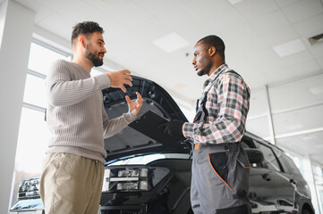 Fototapete - Man on the result of the work of a mechanic. The client evaluates the repair of the car by a mechanic