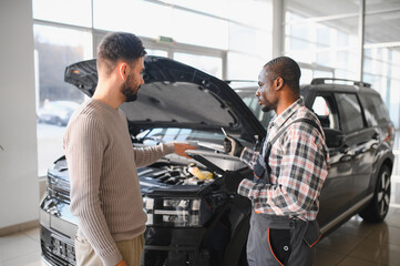 Fototapete - Man on the result of the work of a mechanic. The client evaluates the repair of the car by a mechanic