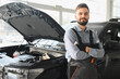 © Serhii - Friendly mechanic in modern car repair shop with car. Professional technician checking vehicle diagnostics and maintenance. Concept of automotive industry and customer service