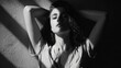 © Justlight - Black and white portrait of a sensual young woman lying down with her arms behind her head, illuminated by beams of sunlight creating a dramatic chiaroscuro effect