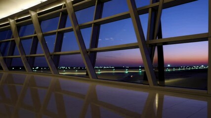 Poster - Sunrise rays streaming through spacious airport terminal windows, highlighting runway, illuminating parked airplanes with warm golden light reflecting on glass surfaces