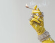 © Sawoon - Yellow latex glove holding lit cigarette smoke pearl diamond rings jewelry ironic luxury cleaner concept surreal pop art style fashion editorial humor minimalist background copy space banner posh chic