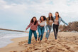 © bernardbodo - Four Young Women Running in a Line Holding Each Other at a Sandy Beach