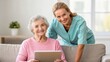 © ng-TDRD - A caregiver and an elderly woman smile together while looking at a tablet, showcasing companionship and technology in daily life.