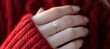 © Nure - Close-up of woman's hand with diamond engagement ring in warm winter light, red sweater adds cozy romantic mood — holiday love and celebration concept