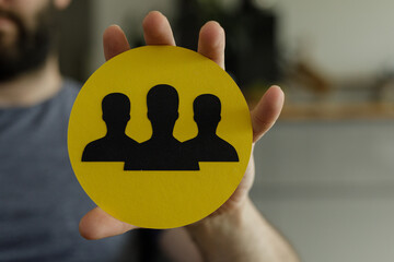 Aufkleber - Image of a hand holding a yellow circle with three black silhouettes representing teamwork and collaboration.