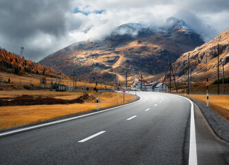 Wall Mural - empty asphalt road winding through alpine mountains in clouds at sunset in autumn. landscape with ma