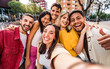 © Davide Angelini - Multicultural cheerful friends taking selfie pic with smart mobile phone device - Youth community people laughing at camera together - Friendship concept with guys and girls having fun outdoors