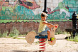 © Luis - Child enjoying a playful ride on a spring toy in a vibrant park setting