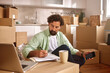 © Stockphotodirectors - A man sits on the floor of a new home, surrounded by unpacked boxes. He writes on a notepad while holding a smartphone, thoughtfully managing his move.