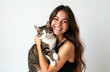 © Vadym - Beautiful smiling brunette girl holds cute tabby cat. Woman and pet cat portrait on white background. Smiling female embraces her cat. Relationship, animal love, tenderness, friendship.