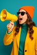 © Imagine  - Trendy young woman in colorful outfit shouting into a yellow megaphone on a vibrant turquoise background, expressing excitement, announcement, or creative communication message