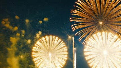 Wall Mural - Firework explosions light up night sky with bright orange and yellow colors, creating festive and joyful celebration filled with vibrant light and color bursts