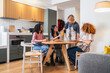© Koldo_Studio - Four young multiethnic friends are sitting at a round table in a modern apartment, enjoying breakfast and conversation