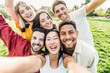 © Davide Angelini - Multiracial friends taking selfie picture with smart mobile phone outside - Group of young people smiling at camera outdoors - Friendship concept with guys and girls enjoying summer vacation